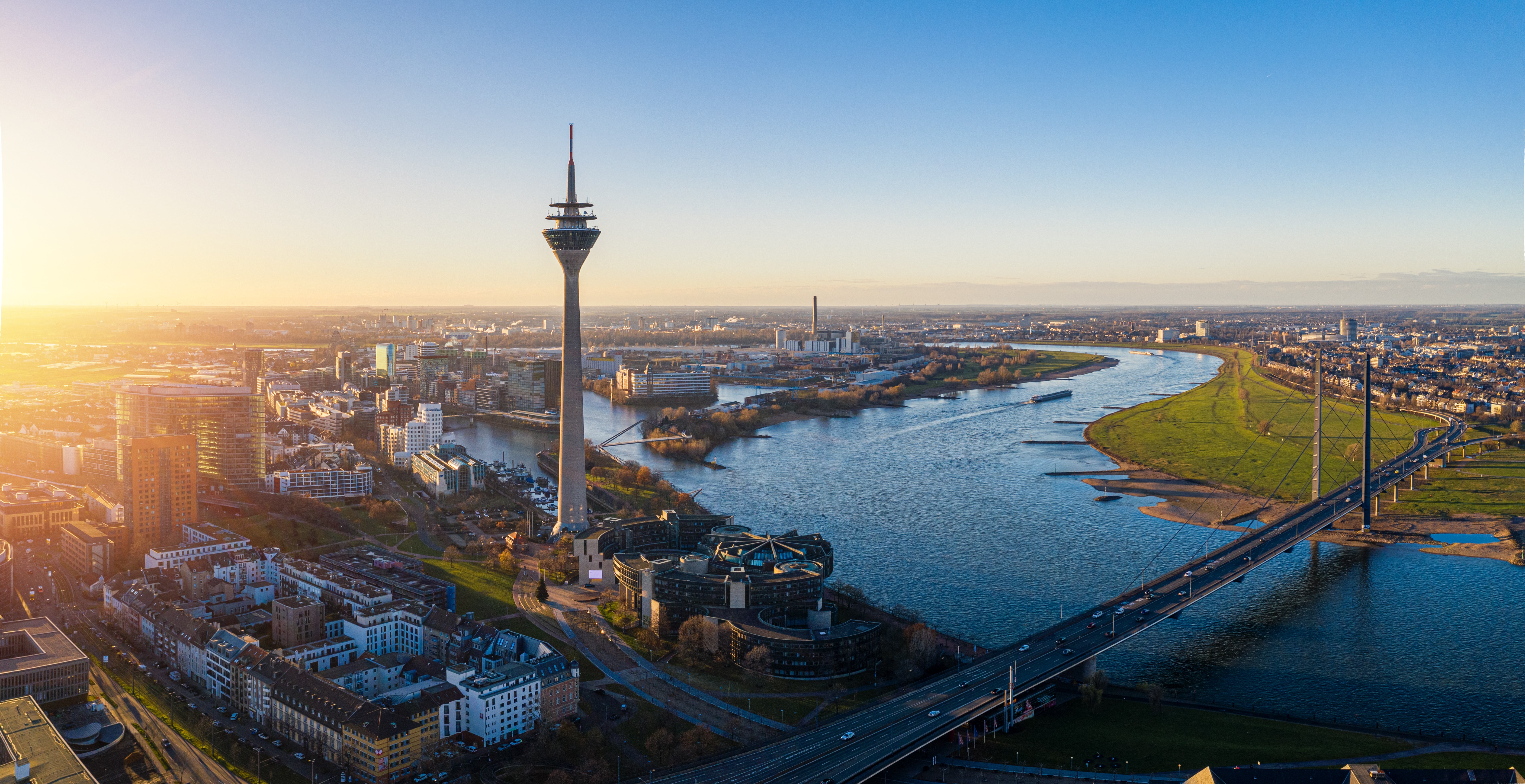 Dusseldorf vanaf boven bekeken met uitzicht op de stad, een grote kronkelende rivier en een hoge radiotoren.
